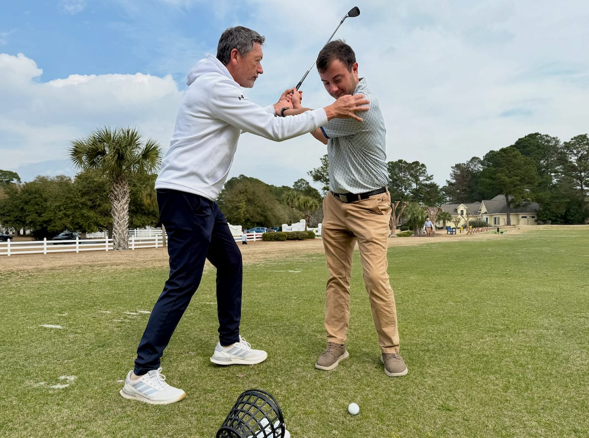 Golf instructor helping a golfer with swing technique
