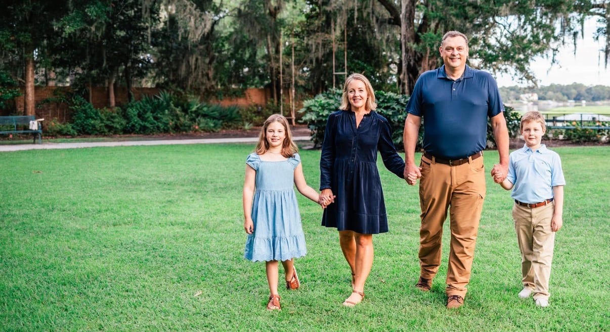 Kate Nolan walking hand in hand with her husband and their two children across a lawn